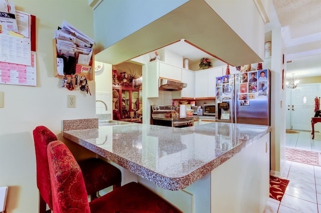 kitchen with white cabinets, a breakfast bar, kitchen peninsula, and appliances with stainless steel finishes