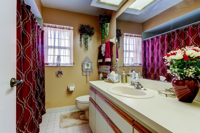 bathroom featuring tile patterned flooring, vanity, a skylight, and toilet