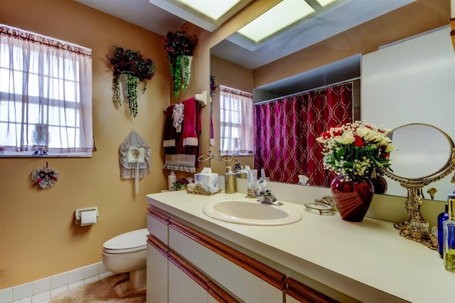 bathroom featuring tile patterned flooring, vanity, toilet, and a healthy amount of sunlight