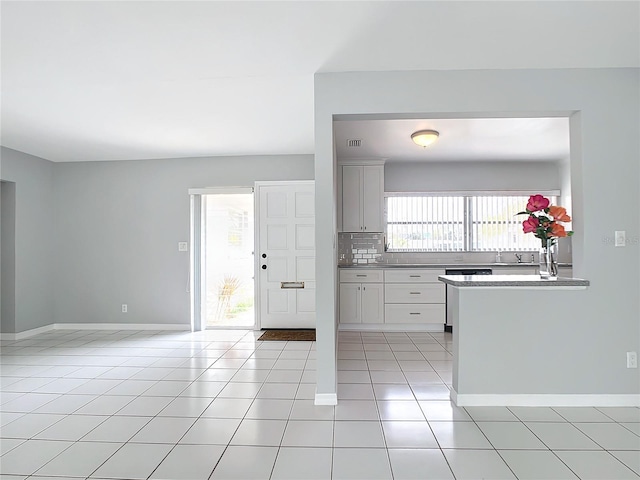 kitchen featuring white cabinets, tasteful backsplash, and light tile patterned flooring