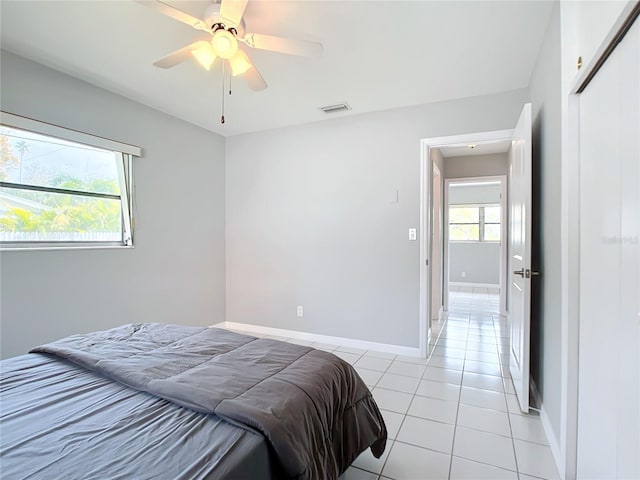 bedroom with ceiling fan, light tile patterned flooring, and a closet