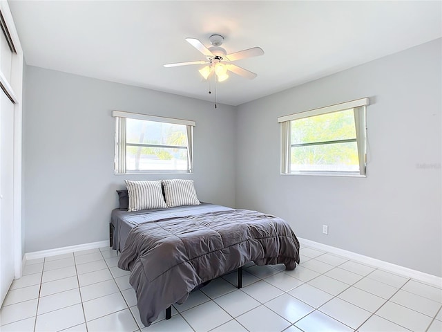 tiled bedroom featuring multiple windows and ceiling fan