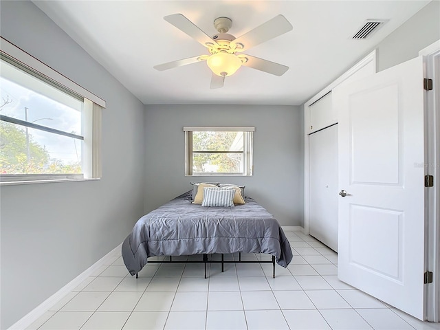 tiled bedroom featuring multiple windows and ceiling fan