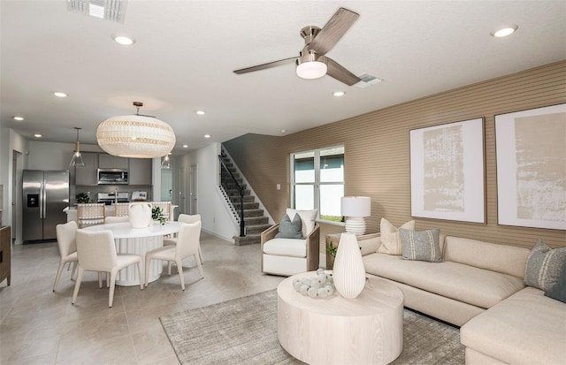 living room featuring light tile patterned floors and ceiling fan with notable chandelier