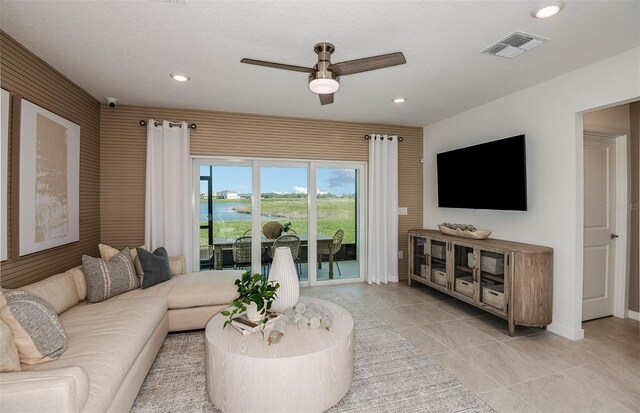 living room with ceiling fan and a textured ceiling