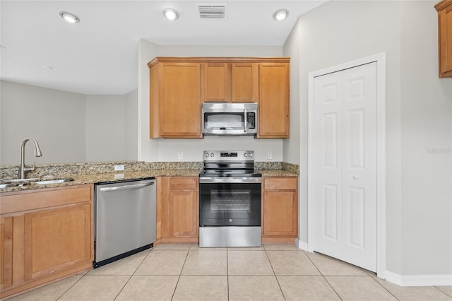 kitchen featuring light tile patterned flooring, appliances with stainless steel finishes, light stone counters, and sink