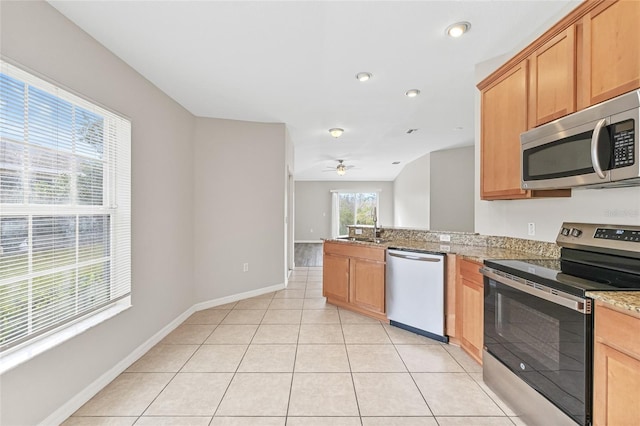 kitchen featuring light stone countertops, stainless steel appliances, ceiling fan, sink, and light tile patterned flooring