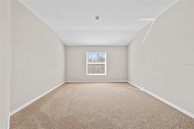 empty room featuring light colored carpet and lofted ceiling