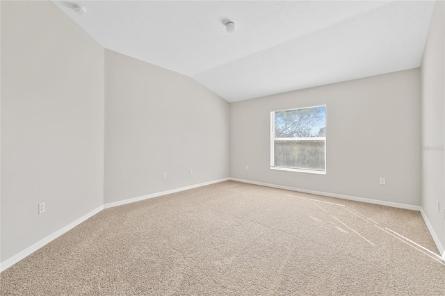 carpeted empty room featuring vaulted ceiling