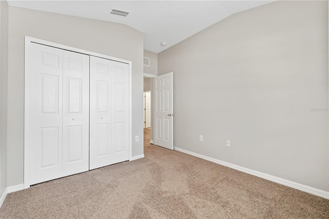 unfurnished bedroom featuring carpet flooring, a closet, and vaulted ceiling