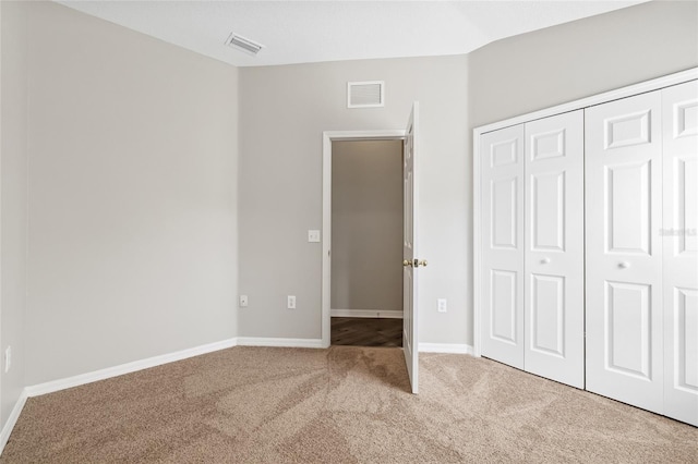 unfurnished bedroom featuring lofted ceiling, carpet floors, and a closet