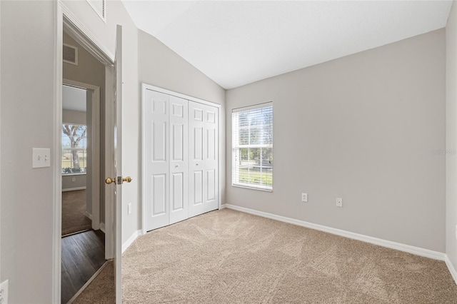 unfurnished bedroom with carpet flooring, lofted ceiling, and a closet