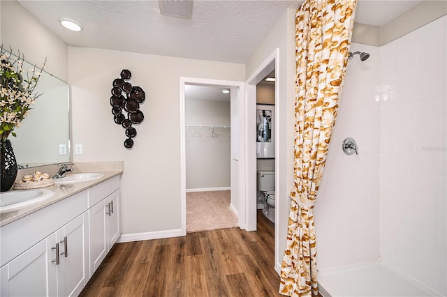 bathroom with vanity, wood-type flooring, a textured ceiling, and toilet