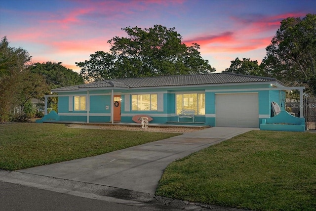 ranch-style house featuring a tile roof, a front yard, stucco siding, driveway, and an attached garage