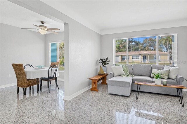 living area featuring plenty of natural light, baseboards, speckled floor, and ceiling fan