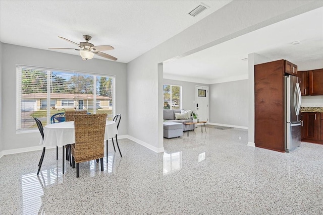 dining room with visible vents, plenty of natural light, light speckled floor, and baseboards