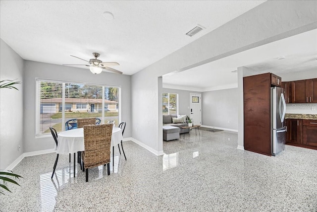 dining area with a textured ceiling, light speckled floor, visible vents, and baseboards