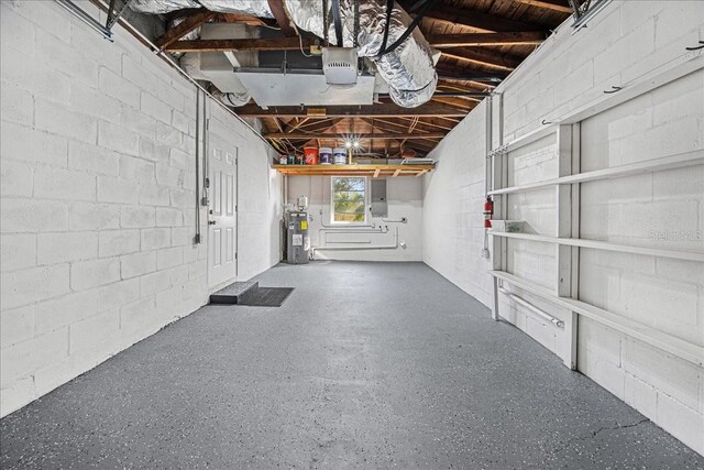 garage with water heater, concrete block wall, a garage door opener, and electric panel