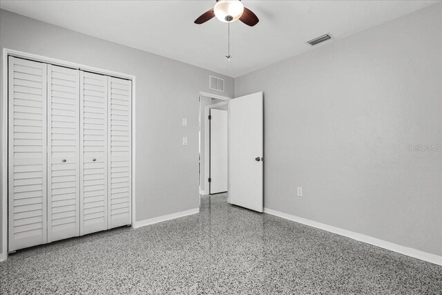 unfurnished bedroom featuring speckled floor, baseboards, visible vents, and a closet