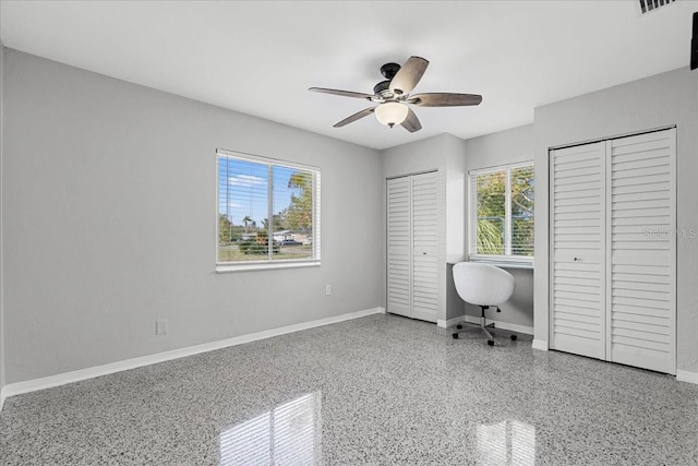 unfurnished office with speckled floor, baseboards, and ceiling fan