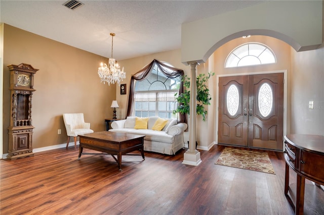 foyer with dark wood-type flooring, a healthy amount of sunlight, and a notable chandelier