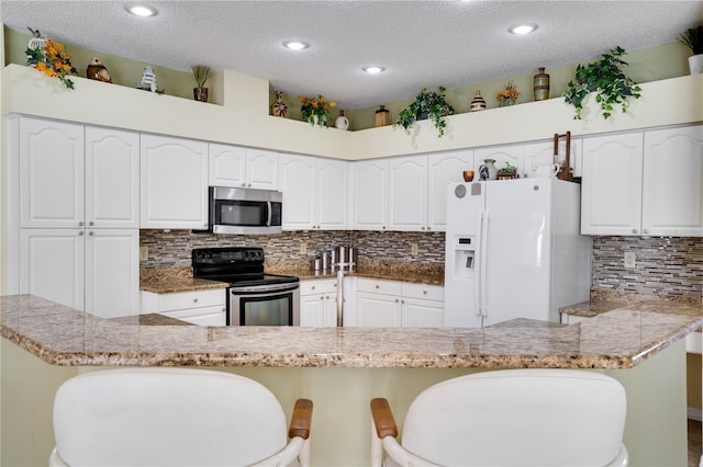 kitchen featuring white refrigerator with ice dispenser, a breakfast bar, kitchen peninsula, and black / electric stove