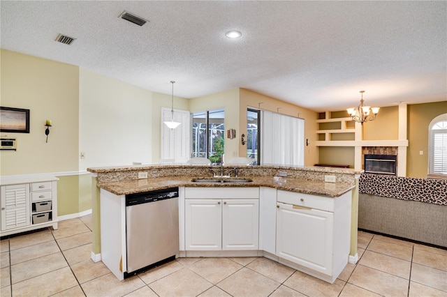 kitchen featuring pendant lighting, stainless steel dishwasher, plenty of natural light, and an island with sink