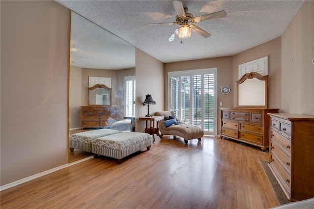 living area featuring ceiling fan, a textured ceiling, and light wood-type flooring