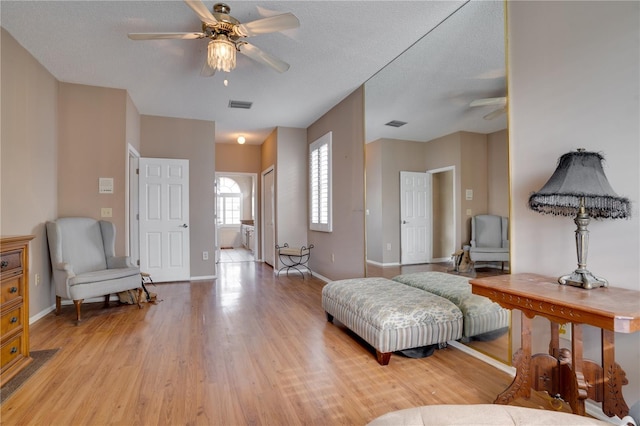 sitting room featuring ceiling fan, a textured ceiling, and light hardwood / wood-style flooring