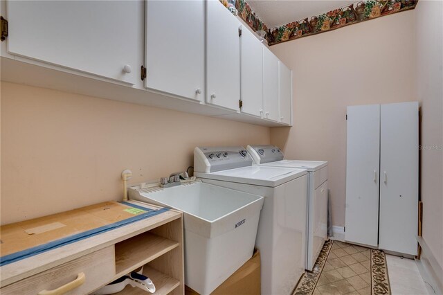 clothes washing area with washer and dryer, cabinets, and sink