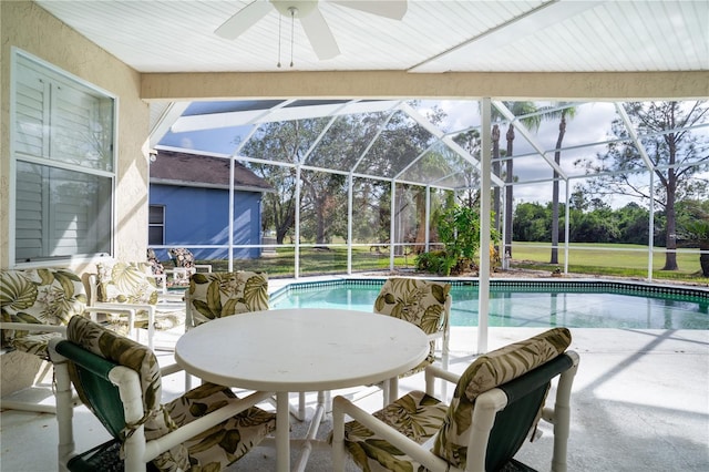 view of swimming pool with ceiling fan, a patio, and glass enclosure