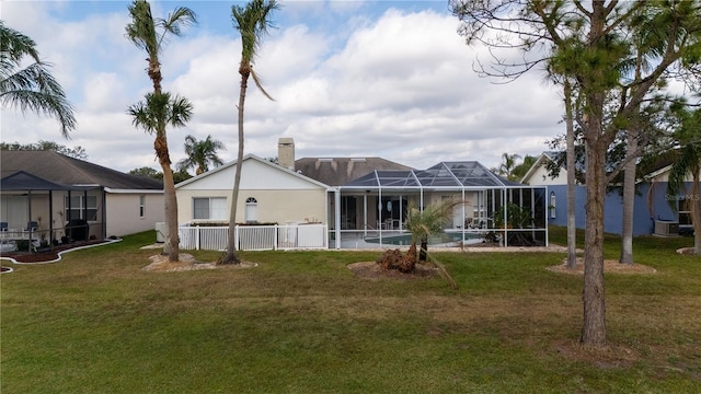 rear view of property featuring a lanai and a lawn