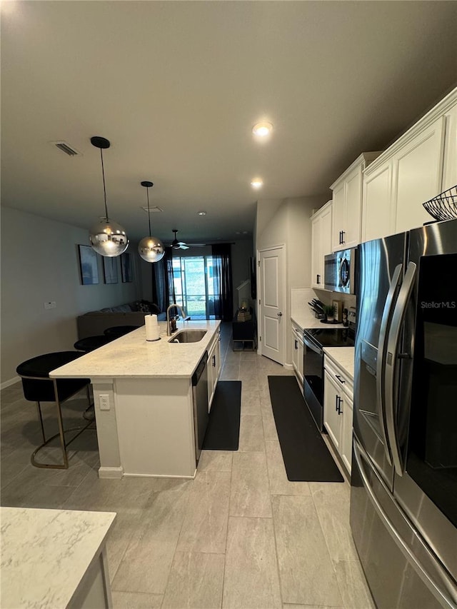 kitchen with a center island with sink, white cabinets, sink, and appliances with stainless steel finishes