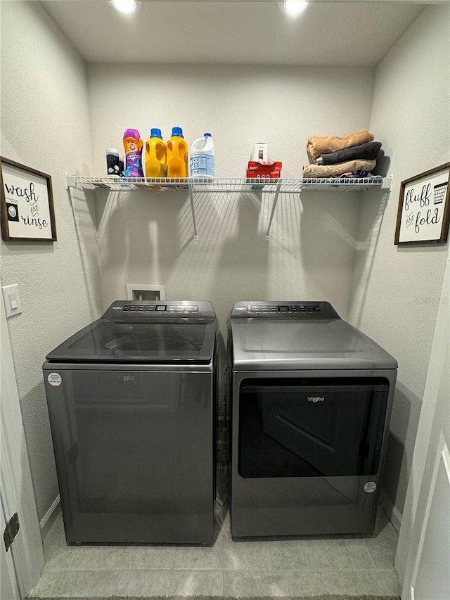 clothes washing area with light tile patterned floors and washing machine and clothes dryer