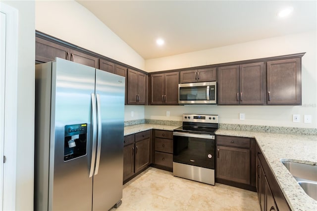 kitchen with light stone countertops, dark brown cabinets, stainless steel appliances, and lofted ceiling