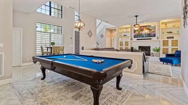 rec room with a tile fireplace, built in features, pool table, a notable chandelier, and light parquet flooring