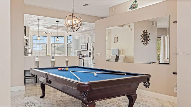 playroom featuring a tray ceiling, plenty of natural light, a notable chandelier, and pool table