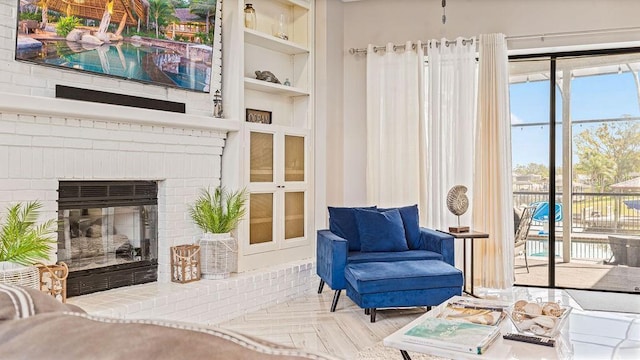 sitting room featuring built in shelves, light parquet flooring, and a brick fireplace