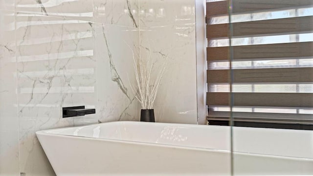 bathroom with a tub to relax in and tile walls