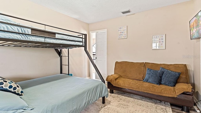 bedroom with a textured ceiling and light wood-type flooring