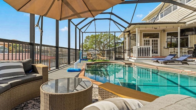 view of pool with outdoor lounge area, glass enclosure, and a patio area