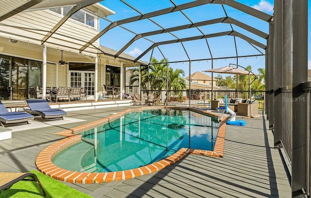 view of swimming pool with glass enclosure, ceiling fan, and a patio