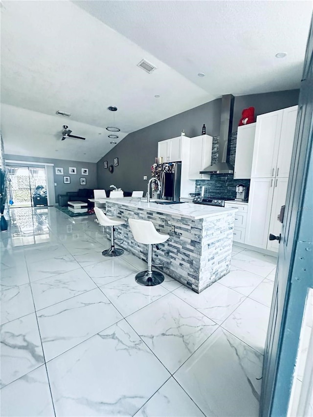 kitchen with white cabinetry, sink, ceiling fan, wall chimney range hood, and lofted ceiling