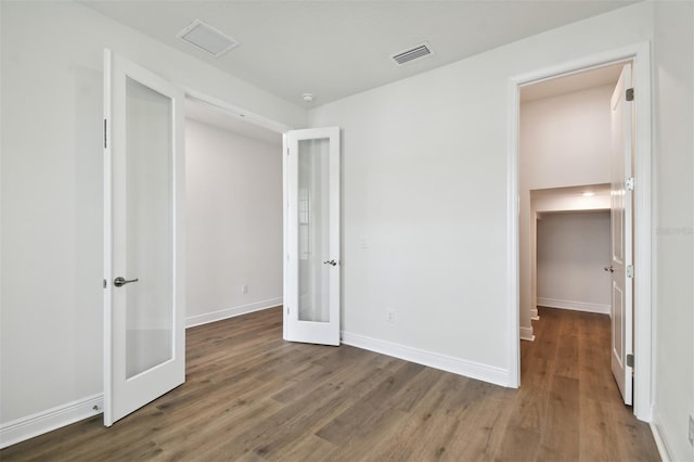 unfurnished bedroom with a closet, dark wood-type flooring, and french doors