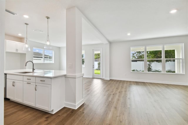 kitchen featuring white cabinetry, sink, hanging light fixtures, and light wood-type flooring