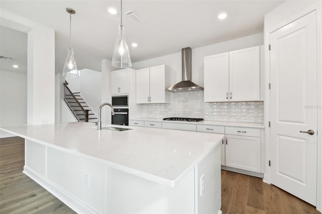 kitchen featuring a spacious island, sink, and wall chimney exhaust hood