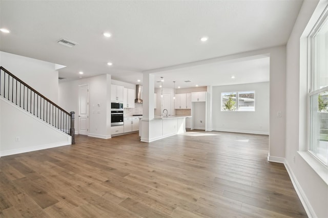 unfurnished living room featuring sink and light hardwood / wood-style flooring