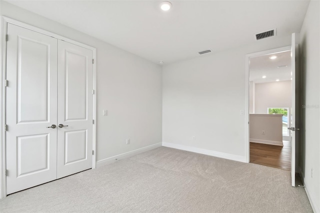 unfurnished bedroom featuring light colored carpet and a closet