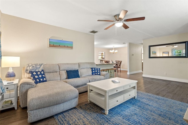 living room with dark hardwood / wood-style flooring and ceiling fan with notable chandelier