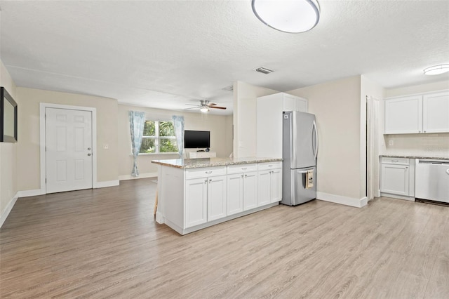 kitchen featuring white cabinets, kitchen peninsula, appliances with stainless steel finishes, and light hardwood / wood-style flooring